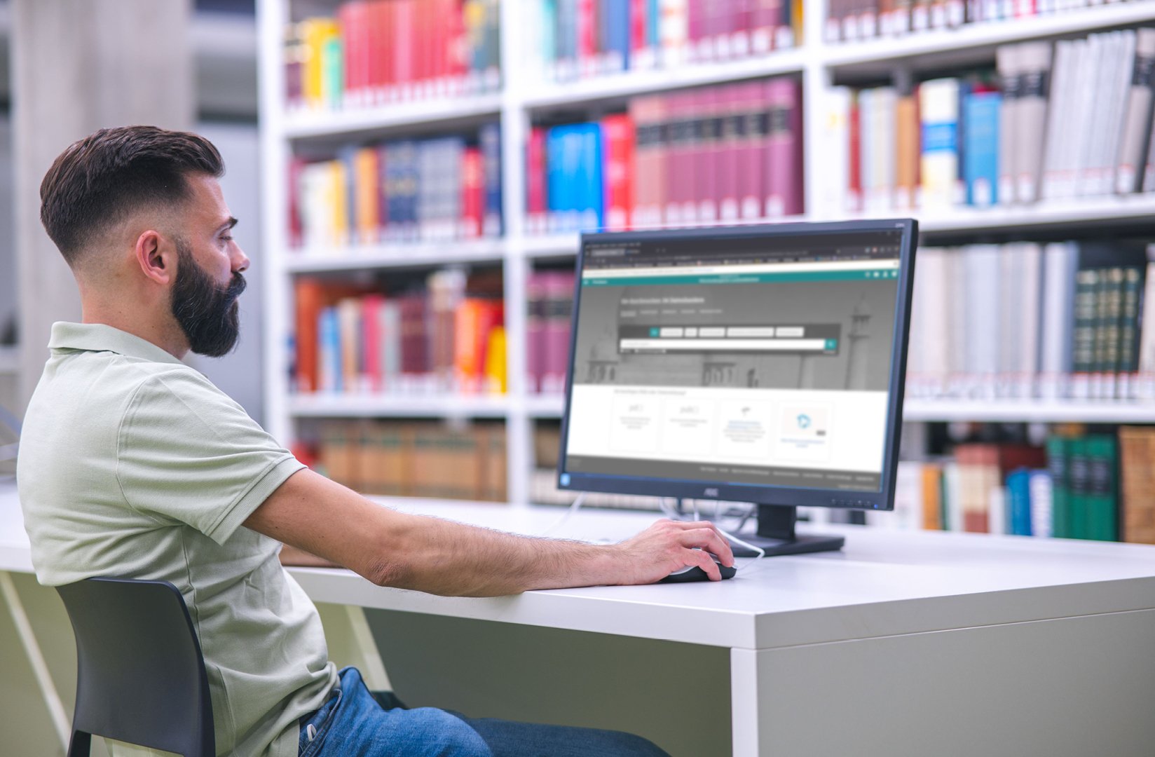 Mann sitzt vor einem Bildschirm und schaut auf eine Datenbank