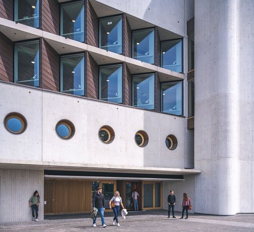 Die Fassade der Württembergischen Landesbibliothek mit Beton und Holz, umgeben von Passanten, die sich unterhalten.